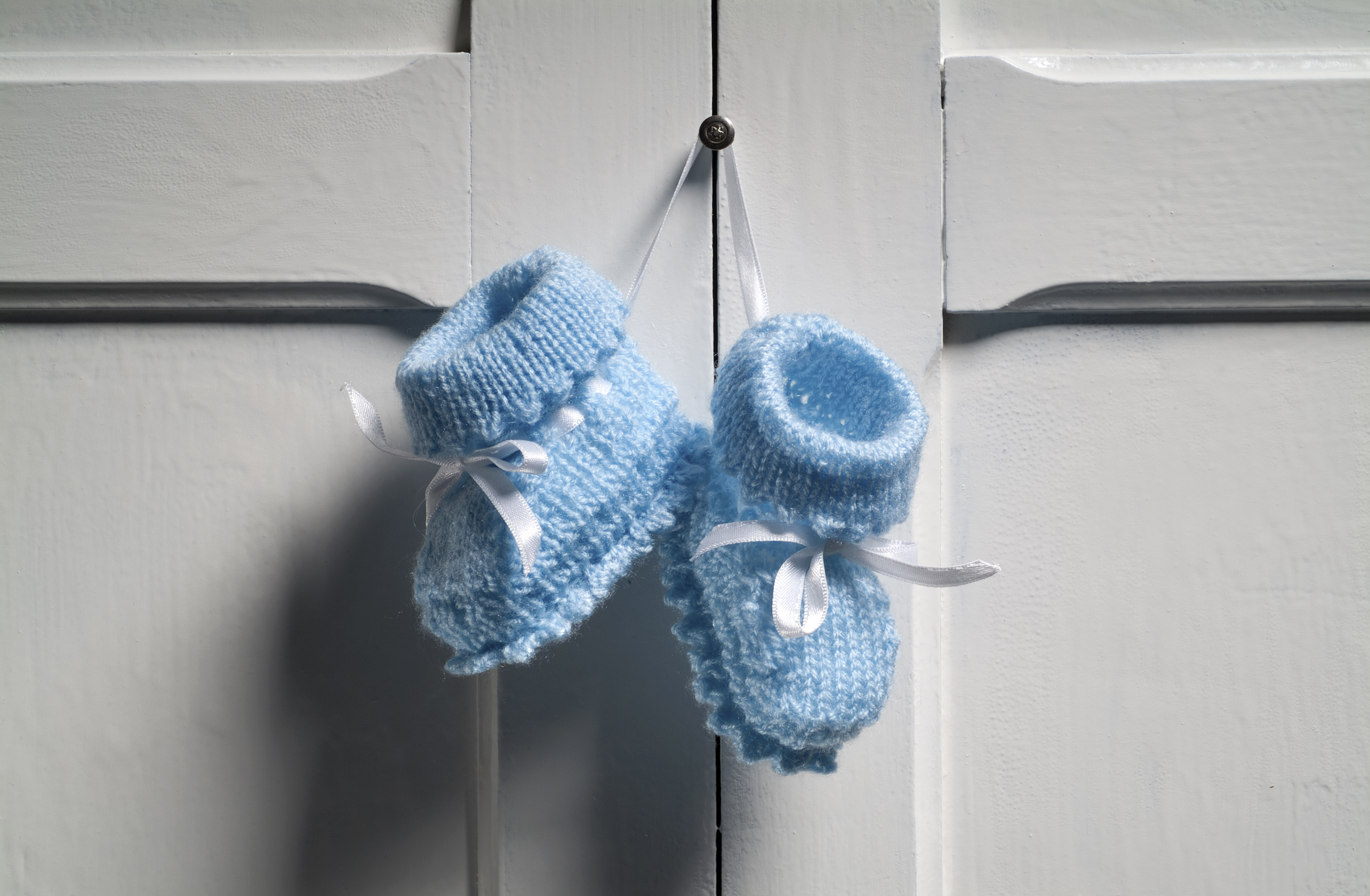 blue baby booties hang on wall